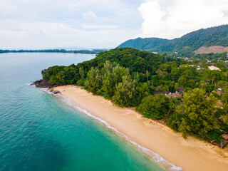 Aerial drone view of Koh Lanta island - the long beach. Famous tropical beach with white sand and turquoise ocean. The island mountains in background.