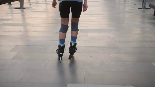 Back view of skater girl riding on rollerblades.