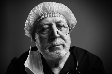 Tired elderly surgeon, in medical uniform, cap, with stethoscope, after work, close-up, portrait, black and white