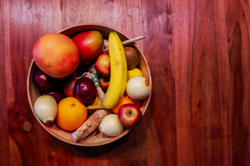 a bowl of fruits and vegetables on a wooden table