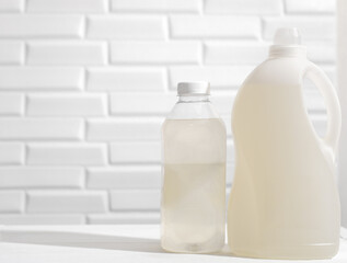 Bottles with laundry detergent and fabric conditioner on white table. Unbranded cleaning products for housekeeping. cleaning liquid products for kitchen chores.