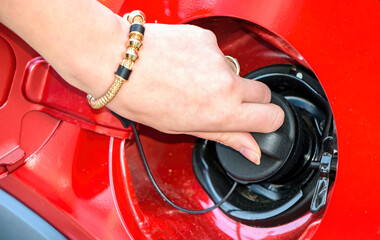A young woman's hand at the fuel tank cap of a car.