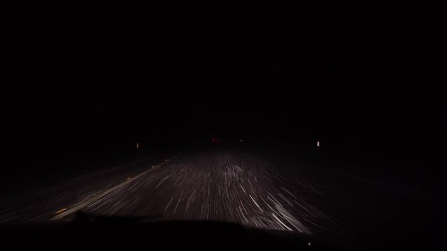 Bad weather, rain and wet snow on the evening dark road. Evening driving, Wet slippery road, rain drops and wet snow on the windshield. car headlights. cars in motion. Traffic in poor visibility