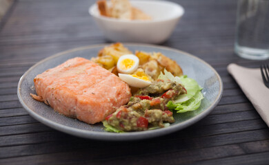 steamed salmon fillet with potato wedges, guacamole homemade and quail egg