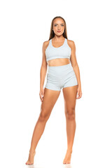 young barefoot sports woman with long hair in a shorts and top on a white background