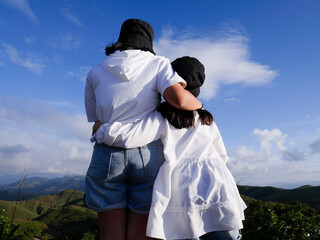 The 2 sisters were hug together with blue sky background