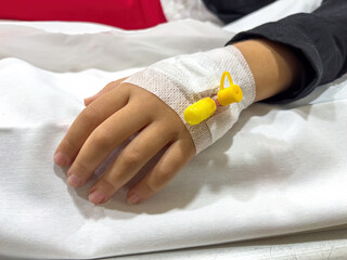 Vascular access on the hand of young sick girl at the hospital bed
