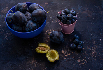 Ripe juicy plums and blueberries in a bowl on a table. Summer fruits.