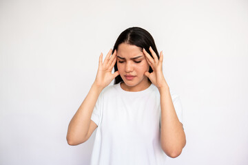 Portrait of tired young woman rubbing head over white background. Caucasian lady wearing white T-shirt suffering from headache or pressure. Exhaustion and migraine concept