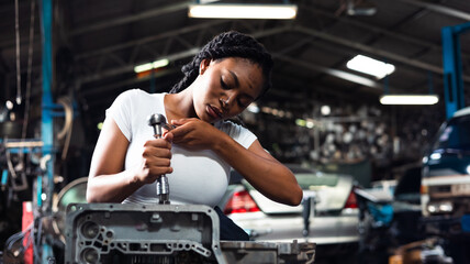 Fototapeta na wymiar African young female car mechanic checking and fixing car engine at service car garage. Black woman mechanic working in car service and maintenance workshop.