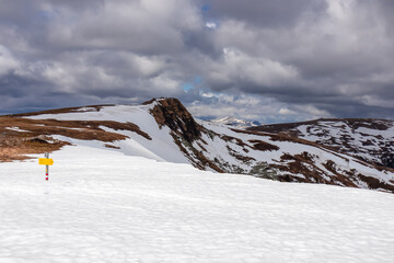 Yellow directional path mark in form of arrow buried in deep snow near Ladinger Spitz, Saualpe,...