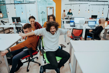 Team building and office fun. Young cheerful businesspeople in smart casual wear having fun while racing on office chairs and smiling.