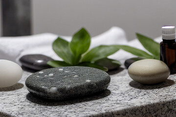 spa beauty treatment relaxing items on granite table with essential oils leaves and meditation...