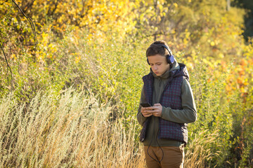 Naklejka na ściany i meble Teenager in headphones with a phone in his hands