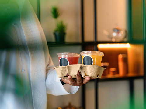 A young menis in a restaurant and holding  fresh orange juice instead of coffee.