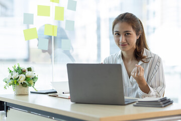 Portrait of a charming Asian business woman working on a laptop in the office.