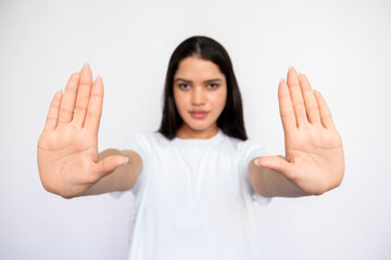 Close-up of female hands making forbiddance gesture over white background. Caucasian lady wearing white T-shirt showing palms. Denial and refusal concept