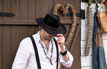 country groom in a black hat and white shirt in the village. Country wedding