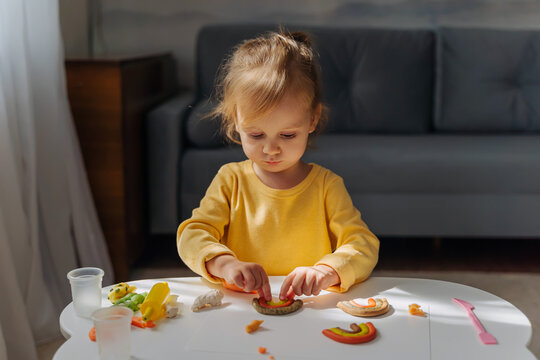 A little girl playing with rainbow from play dough for modeling. Art Activity for Kids. Fine motor skills. Sensory play for toddlers.