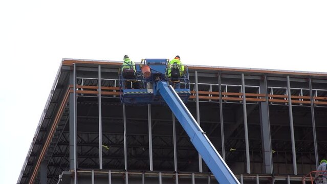 Two workers operate the blue Articulated Boom Lift or telescopic boom lifts and truck-mounted bucket crane to ensure safety when working at height and lifting the articulated boom to high heights.
