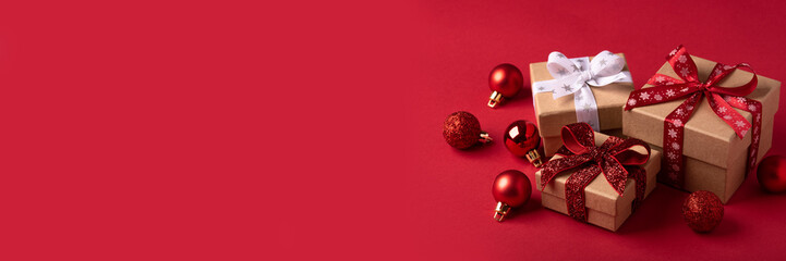 Obraz premium Christmas gift boxes with red balls on red background.