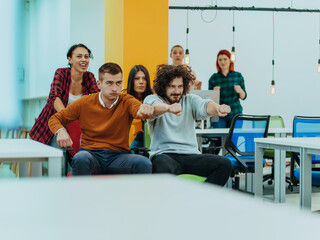 Team building and office fun. Young cheerful businesspeople in smart casual wear having fun while racing on office chairs and smiling.