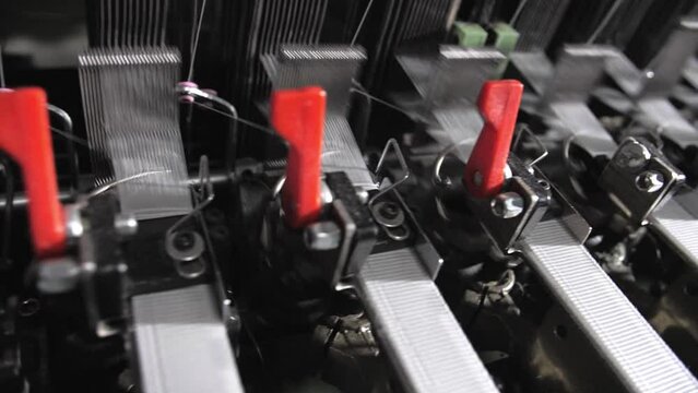Close up of textile machine in slow motion. Fibre thread lines on the weaving loom machine. A loom machine for clothing or woven clothes. Weaving machine for garment industry.