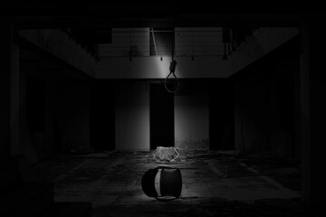 Monochrome shot of a building with a chair on the floor and a loop of rope, a concept of the suicide
