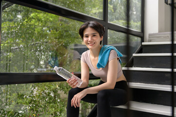 An Asian young woman is  drinking fresh water after exercise at home , healthy lifestyle concept