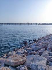 Fototapeta na wymiar Sunny coastal scenery with a blue sea and a bridge in the distance