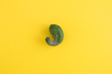 Ugly food. Cucumber on the yellow background. Top view. Copy space.