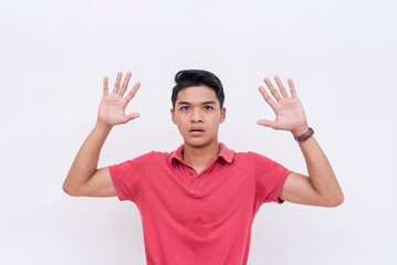 Naklejka premium A young man surrenders, putting both hands in the air. Yielding, being submissive or under arrest. Isolated on a white backdrop.