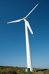 Low angle of a windmill turbine against a blue sky