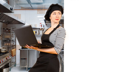 Woman cook. Restaurant chef with laptop. Restaurant owner next to white banner. Female chef uses computer while standing in kitchen. Girl confectioner. Copy space. Concept of software for chefs