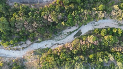 Aerial view of a dry river with sandy bed and banks, with slightly dry surroundings on a sunny day