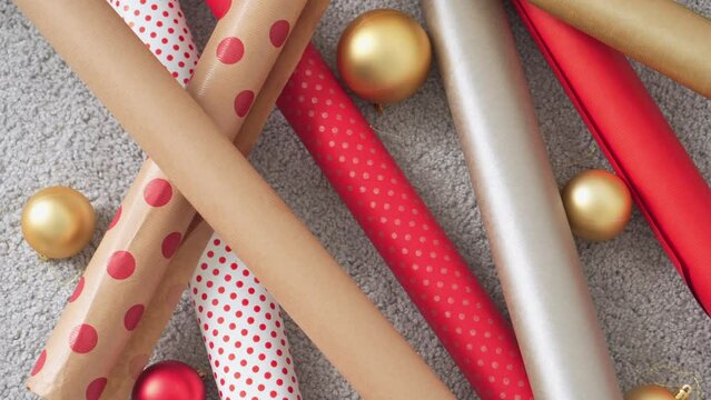 Girl in a Santa hat creates New Year's packages from red wrapping paper. Young woman is packing Christmas presents for her friends and relatives. Decorations, preparation for the winter holiday season