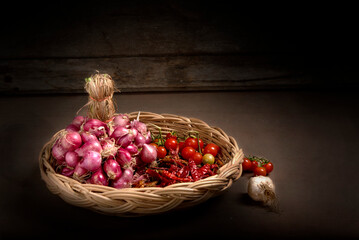 The condiment consists of onions, red peppers and tomatoes in baskets on a wooden floor in the kitchen.