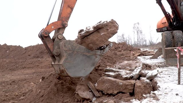 Closed up of a digger bucket picking up earth anding round. Video shot of Construction Excavator Scooping and Dumping on Dirt Pile