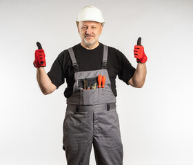 Satisfied Builder. Man foreman shows thumb up. Builder in work overalls and white safety helmet....