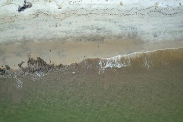 Top view of the waves of a sea hitting the sandy beach during the daytime