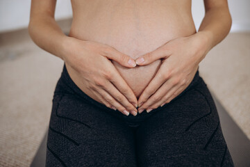 Pregnant woman hugging her belly with hands