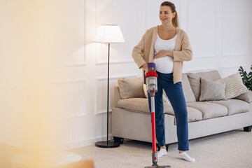 Pregnant woman vacuuming home with rechargeable vacuum cleaner