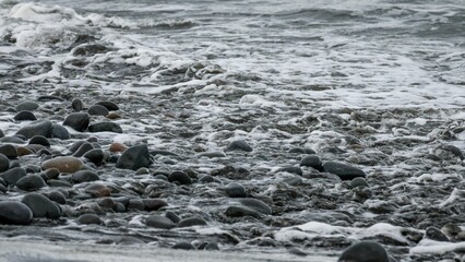 Gray scale shot of the beach shore full of small rocks