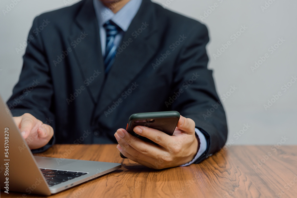 Poster business man working on laptop computer and using mobile phone on desk.