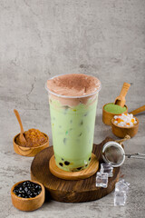 Boba or tapioca pearls is taiwan bubble milk tea in plastic cup with matcha flavor and cream on texture  background, summers refreshment.