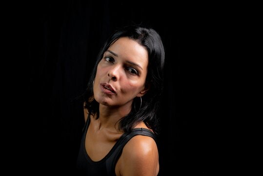 Caucasian young woman looking at camera against simple studio black background