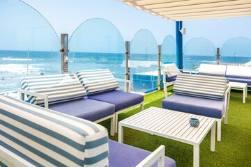 Cafe tables and chairs with blue and white strips with a great view of the sea