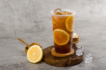 sweet lemonade tea in plastic cup with iced on texture  background, summers refreshment.