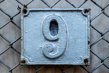 Old retro weathered cast iron plate with number 9 closeup