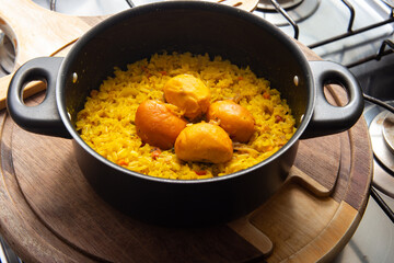 Uma panela preta com arroz com pequi sobre uma tábua de madeira no fogão. Um prato típico...